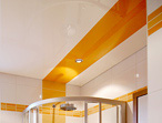 Ansicht eines weien Badezimmers mit weißer Hochglanzdecke. Orange Streifen in Fliesen und Decke dienen als Gestaltungselemente.